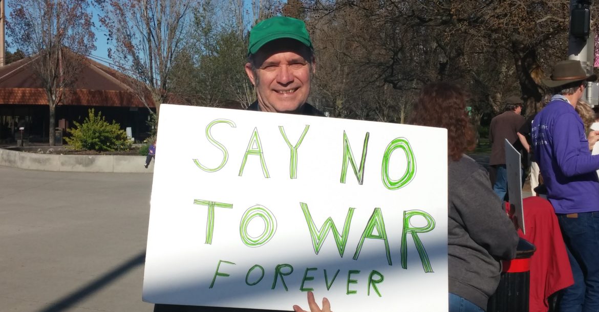 Man holding "Say No To War Forever" sign